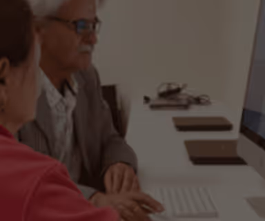 Two people working together at a desk on a computer.