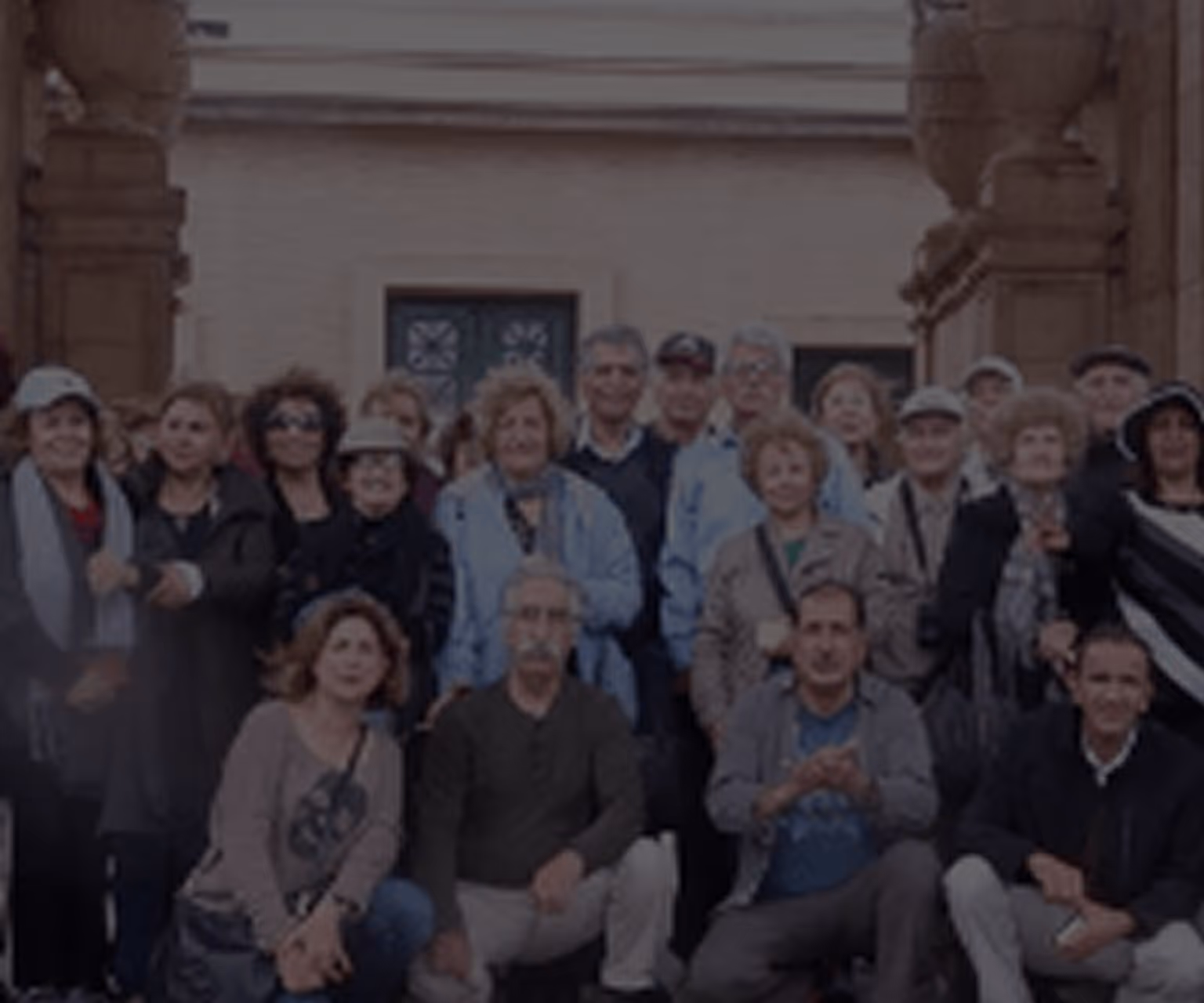 Group of diverse older adults smiling and posing together outdoors in front of a building.