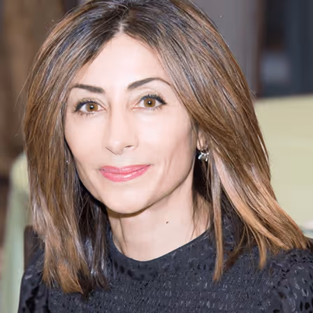 Portrait of a woman with shoulder-length brown hair wearing a black top and small earrings.
