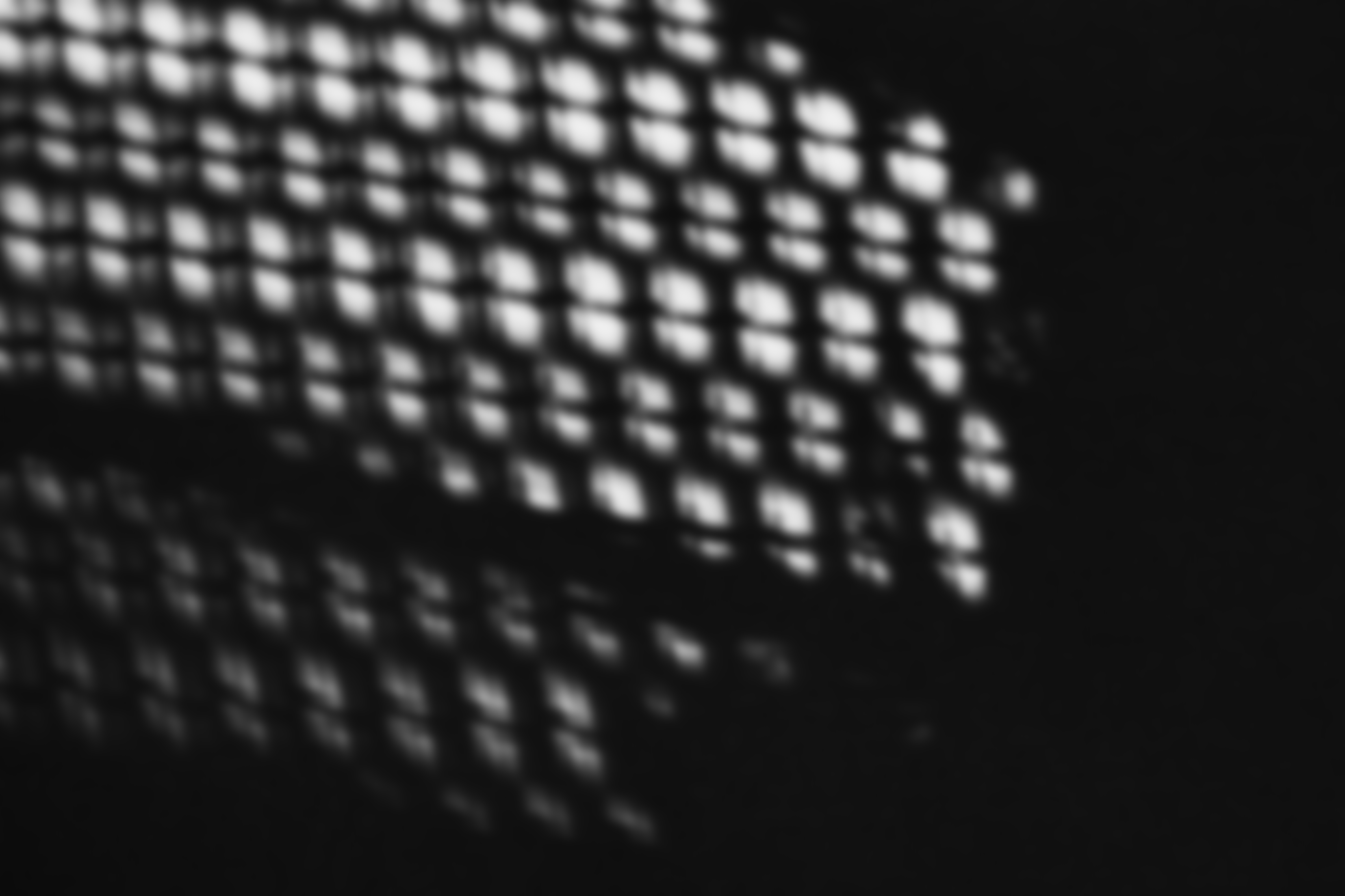 Unscharfe Aufnahme von hellen Lichtflecken in einem quadratischen Gittermuster auf dunklem Hintergrund.