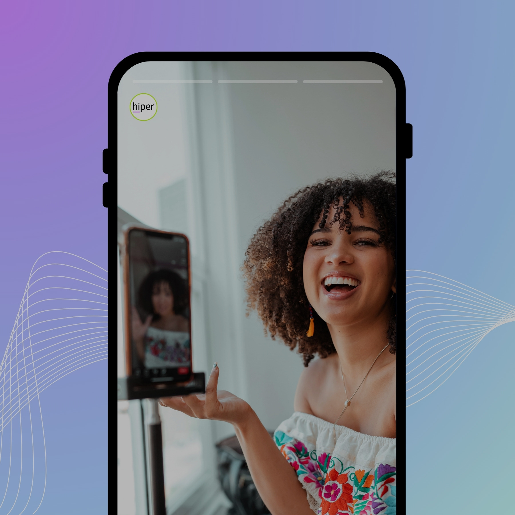 Smiling woman with curly hair and floral off-shoulder top holding a smartphone on a tripod during a video recording.