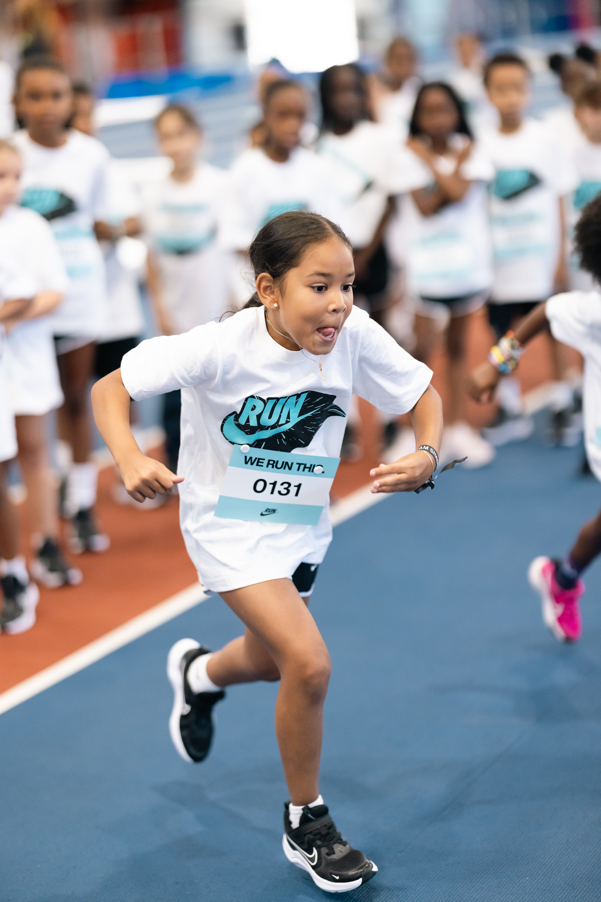 A girl wearing Nike gear runs in front of a group of other children.