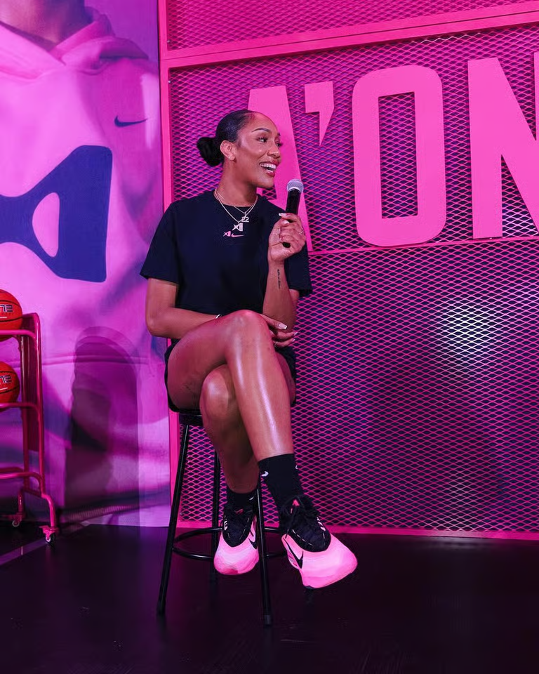 A'ja Wilson sits on a stool, speaking into a microphone and smiling.