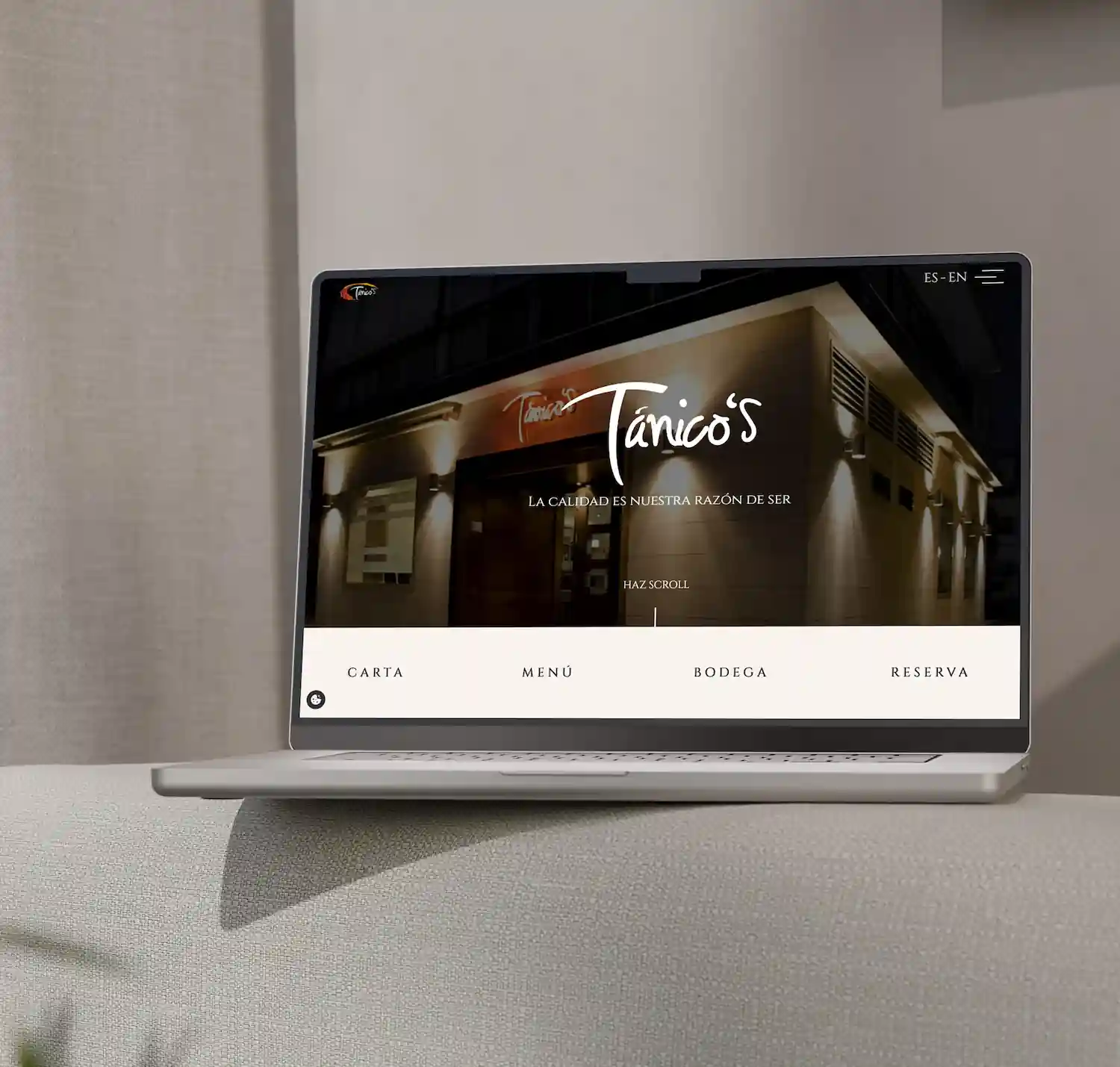 Macbook con una web en pantalla apoyado sobre una cama