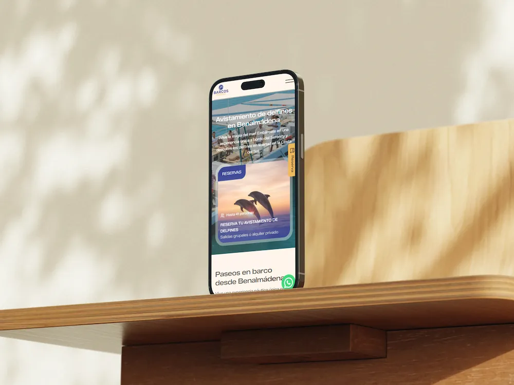iPhone 17 apoyado sobre una tabla de madera mostrando la web de Barcos Málaga
