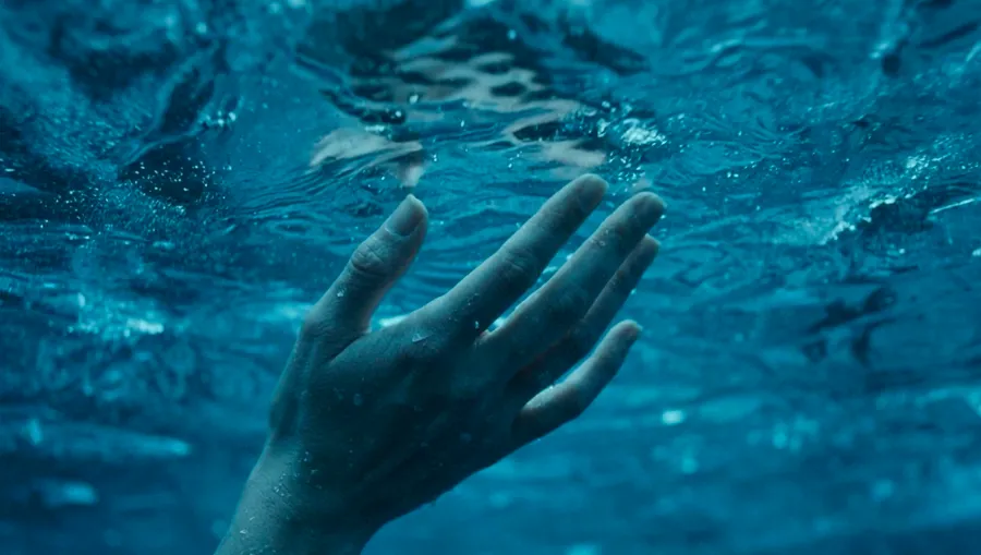 Close-up of a hand reaching through underwater blue light — ai video production by Detroit AI Production House, image generation & art direction by Pierrick Jégou