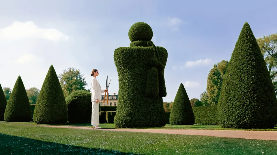Woman in white suit facing an oversized topiary figure in a formal garden for Parfums de Marly — ai advertising agency Detroit, photography & DA by Alex