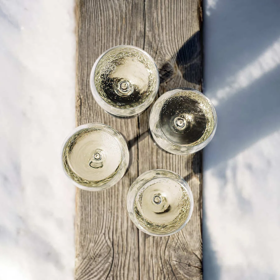 Four Dom Pérignon champagne glasses arranged from above on a weathered wood plank set in fresh snow — ai video production Detroit, photography & art direction by Pierrick Jégou
