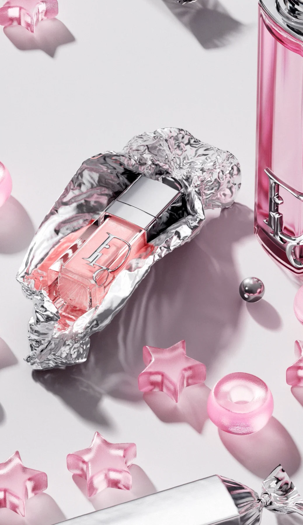 Close-up of a Dior Addict lip oil nestled in foil with a pink bottle and metallic sphere at the edge of frame — ai advertising agency Detroit, photography & art direction by Detroit AI Production House