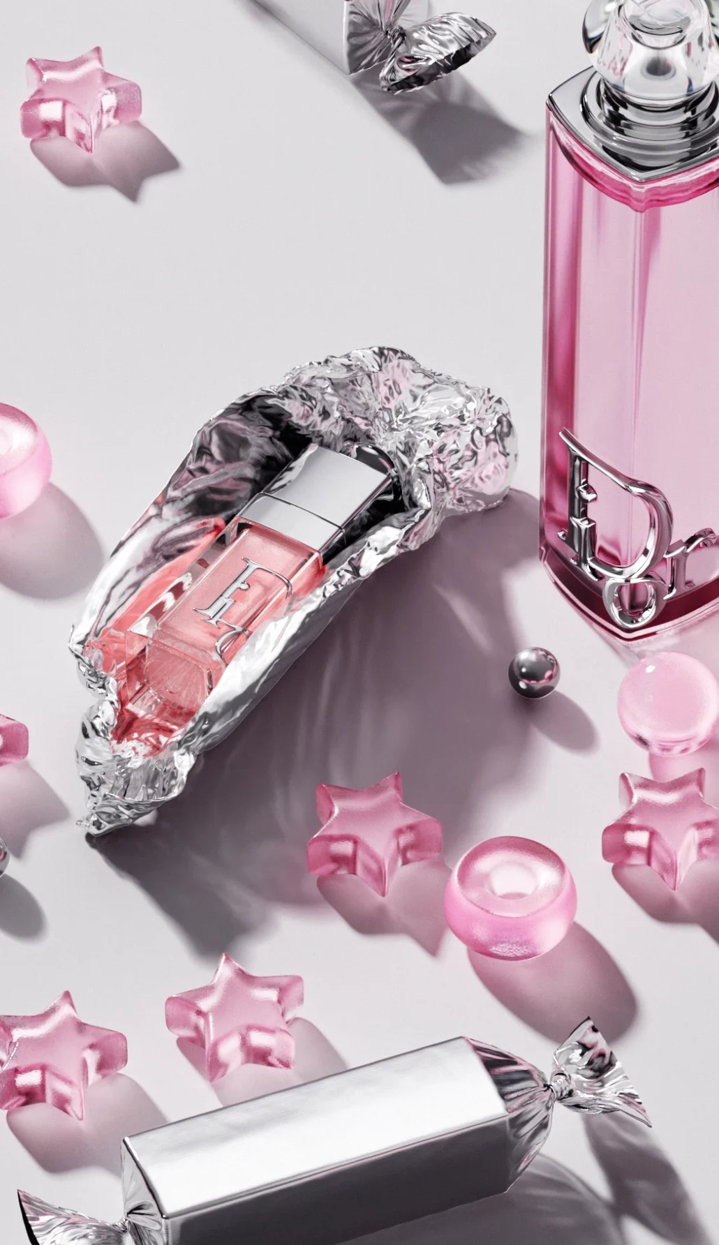 Dior Addict lip oil unwrapped from crumpled silver foil beside pink glass droplets and star-shaped candies — 3d product visualization Detroit, photography & art direction by Detroit AI Production House