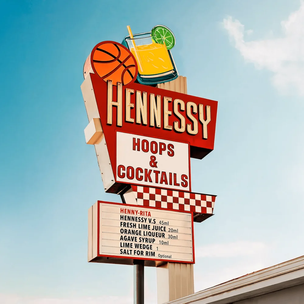 Vintage roadside sign reading "Hennessy Hoops & Cocktails" against a clear blue sky — ai advertising agency Detroit, photography & art direction by Detroit AI Production House