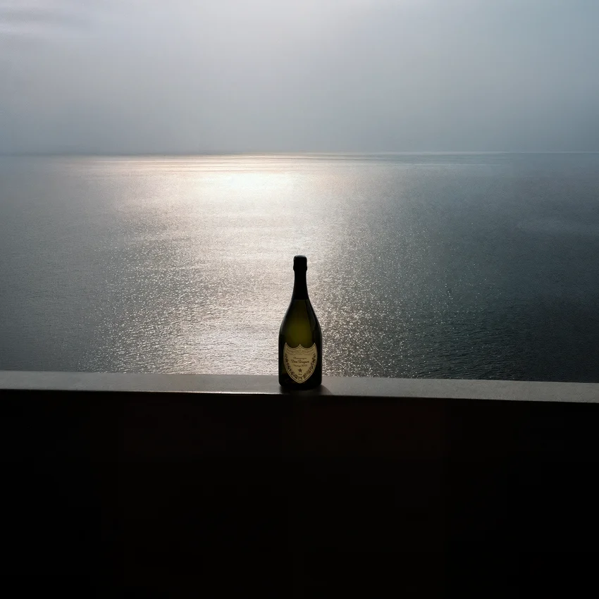 Dom Pérignon bottle silhouetted against a calm sea horizon with sunlight glinting on the water — virtual production studio Detroit, photography & art direction by Pierrick Jégou, produced by Detroit AI Production House