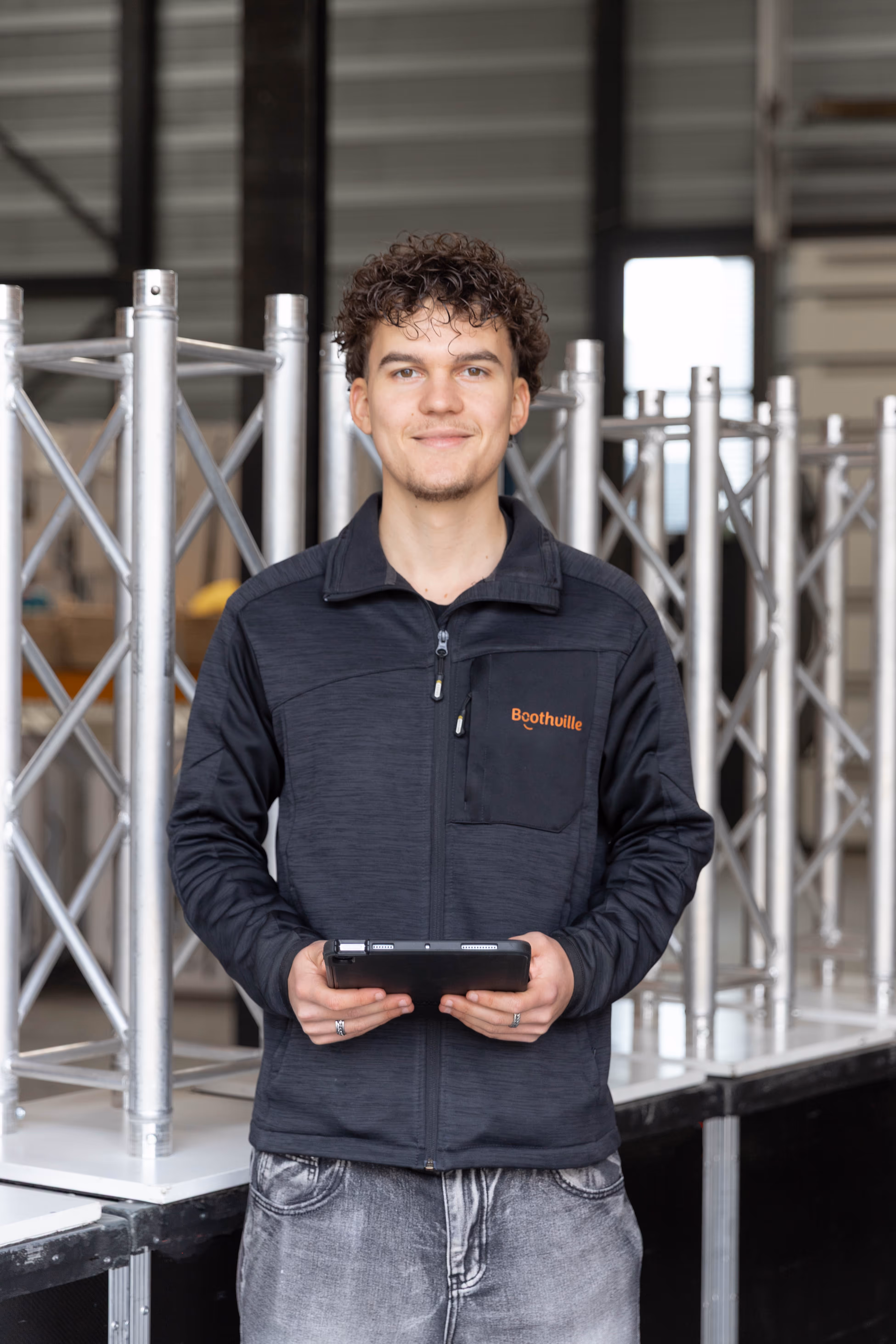 Teamleider in Boothville-jas staat met tablet voor photobooths in het Boothville magazijn.