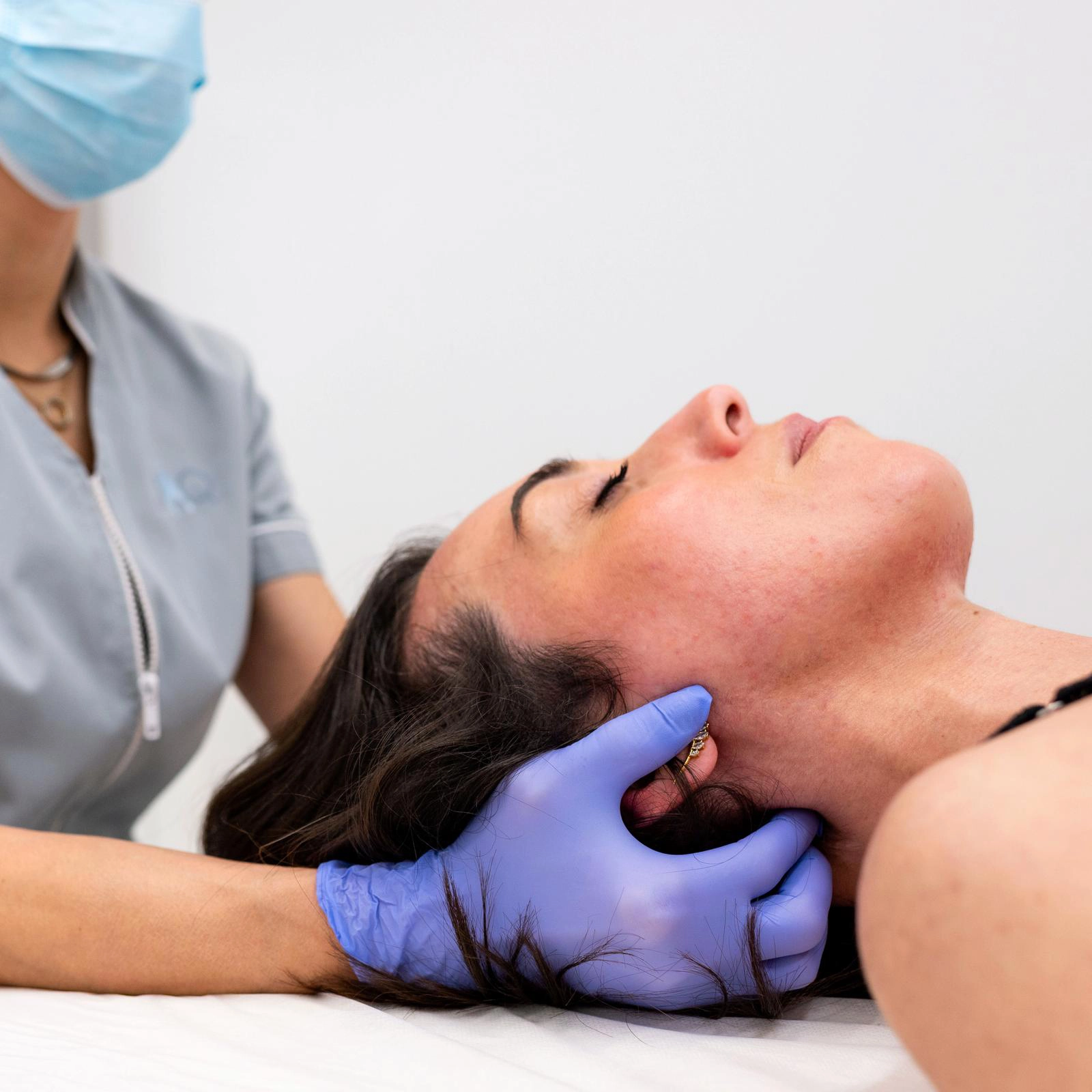 Avaliação manual da articulação temporomandibular e da musculatura cervical durante abordagem clínica para disfunção temporomandibular (DTM), com foco no alívio da tensão e melhoria da mobilidade.