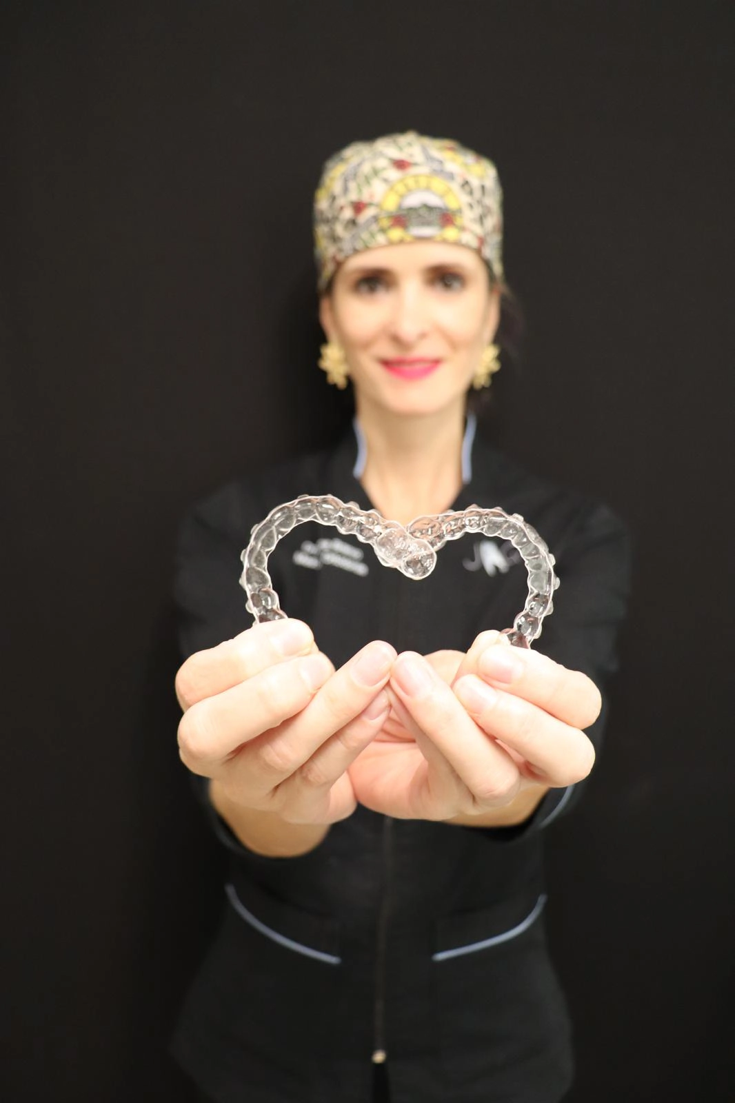 Alinhador dentário transparente utilizado em tratamento ortodôntico, apresentado pela profissional de saúde oral.