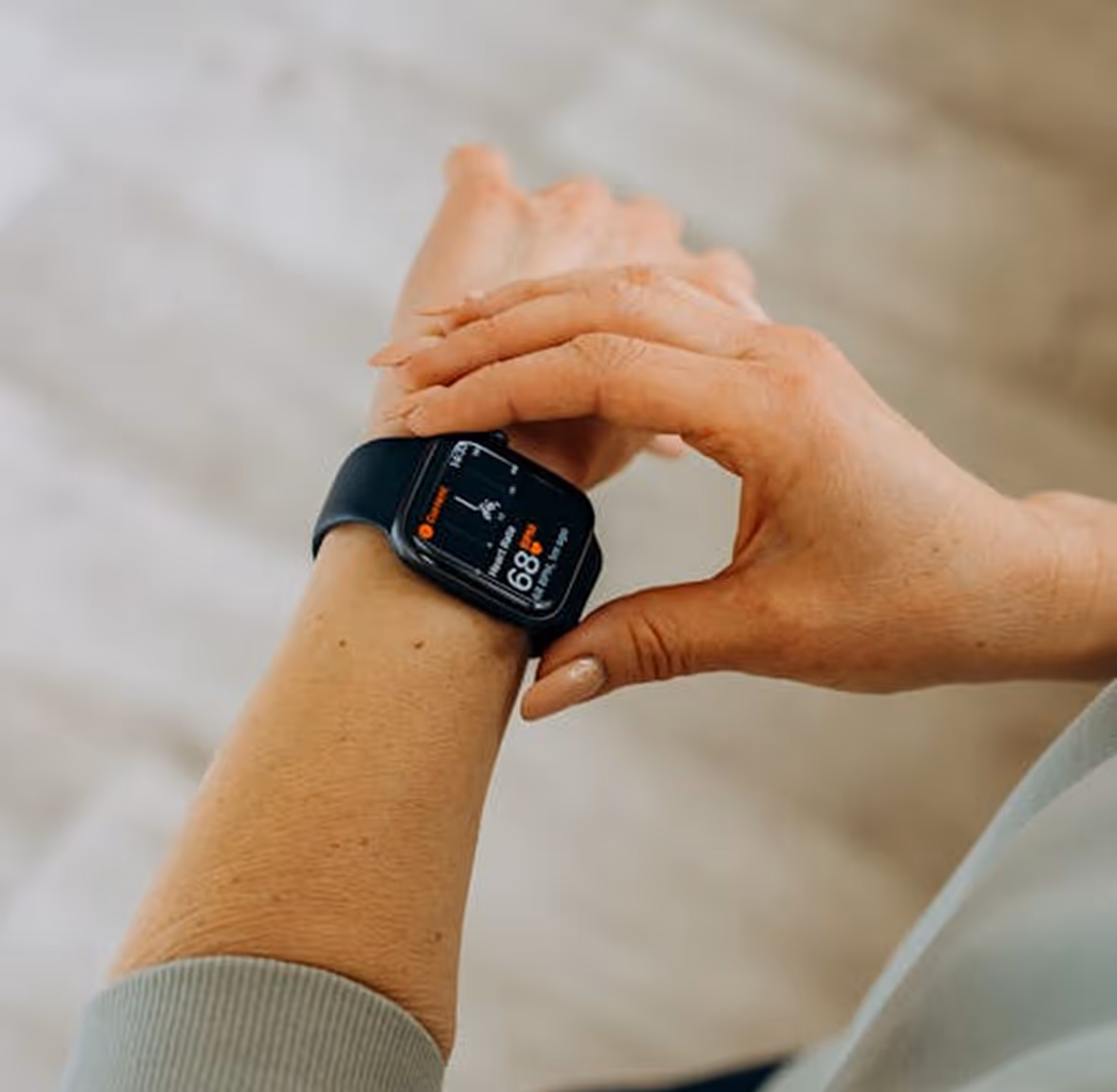 Person adjusting a black smartwatch displaying activity and heart rate data.