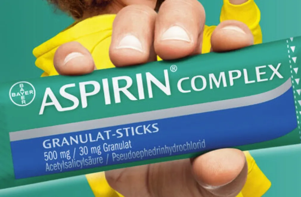 Hand hält eine Packung Aspirin Complex Granulat-Sticks mit 500 mg Acetylsalicylsäure und 30 mg Pseudoephedrinhydrochlorid.