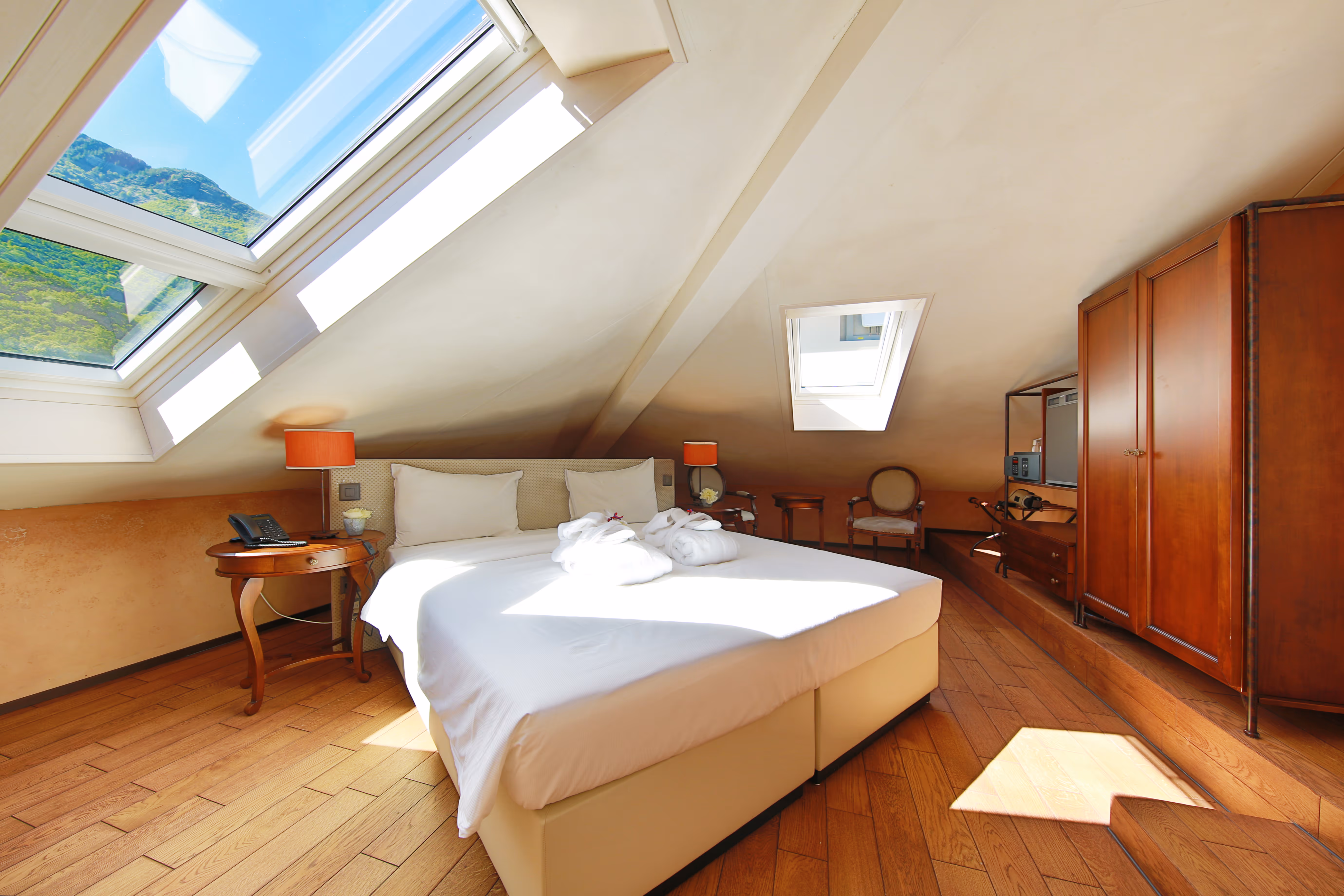 Junior Loft mansardé lumineux à Bellinzone avec grande lucarne vue sur les montagnes, lit double et parquet.