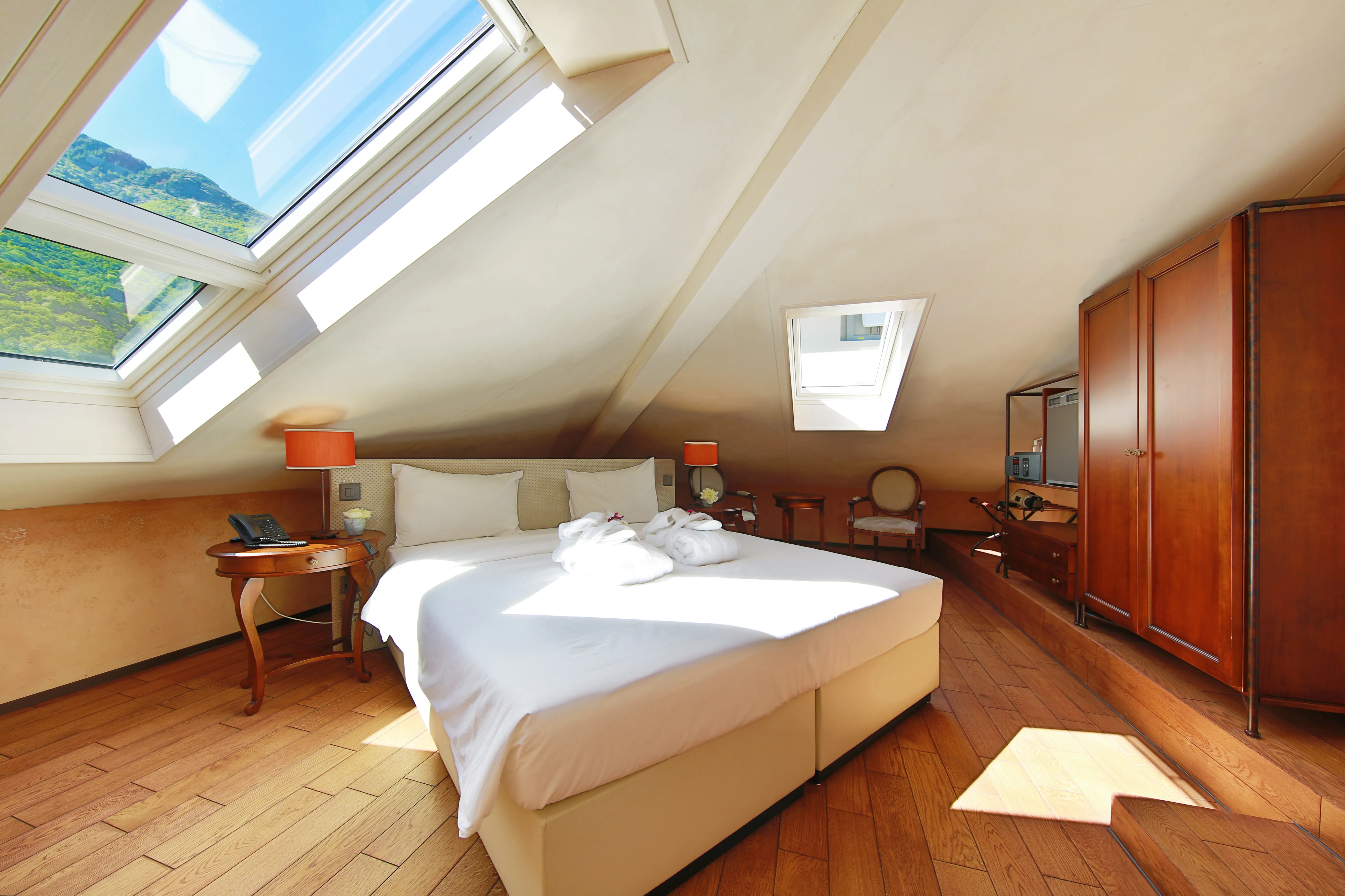 Junior Loft mansardé lumineux à Bellinzone avec grande lucarne vue sur les montagnes, lit double et parquet.
