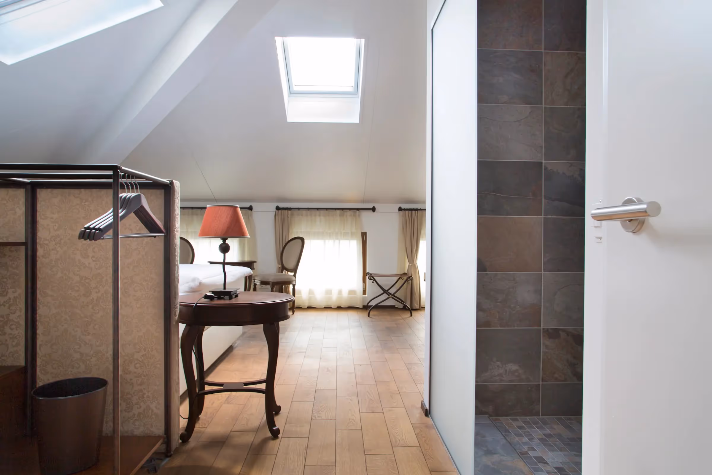 Design Loft con vista bagno: Prospettiva dall'area living verso il bagno moderno con rivestimento in pietra scura e lavabo sospeso.