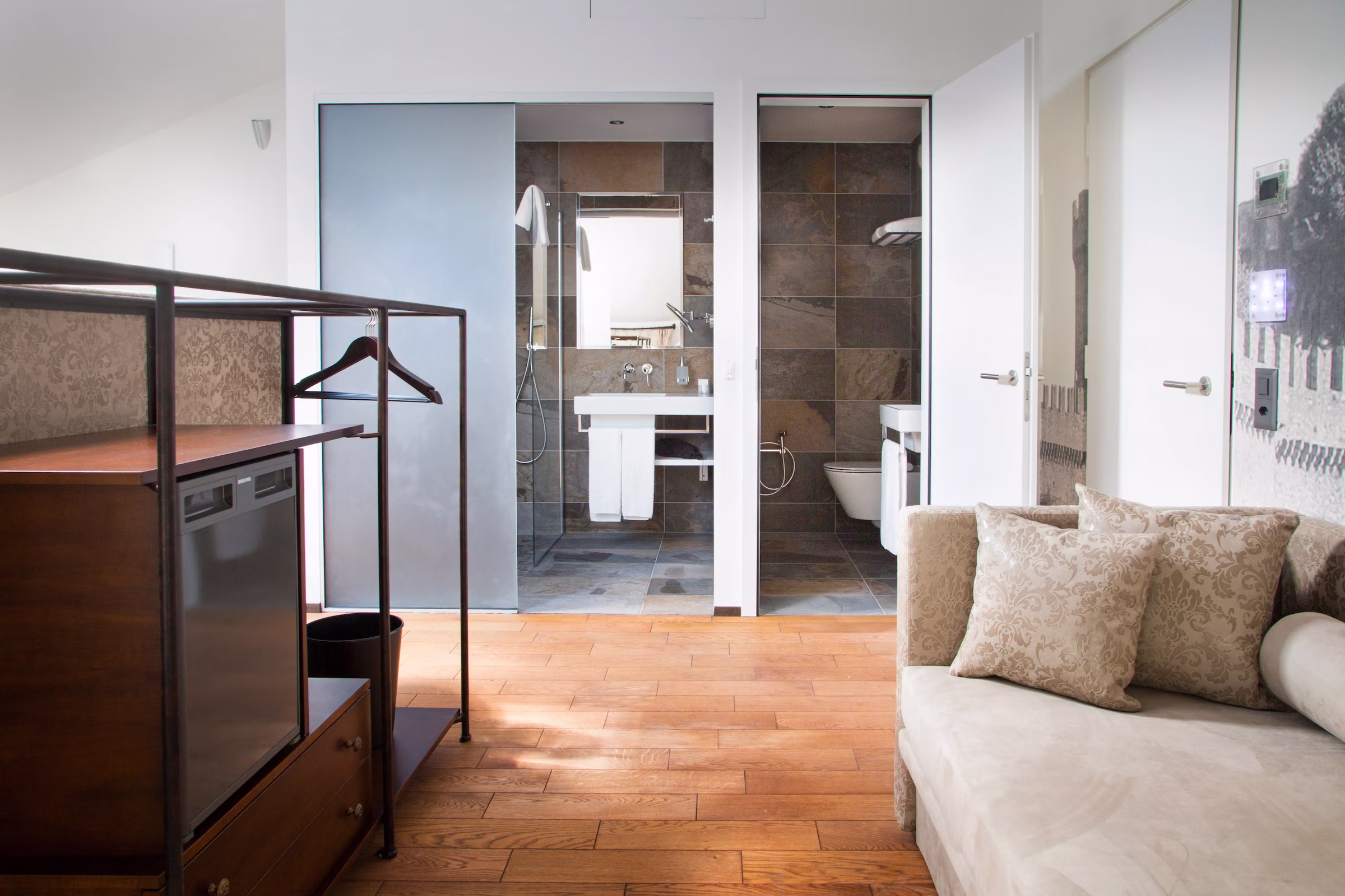 Dettaglio arredi e servizi: Vista dell'angolo bar e armadio aperto accanto all'area living, con doppie porte d'accesso alle zone del bagno sullo sfondo.