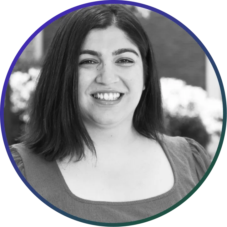 Smiling woman with shoulder-length dark hair wearing a square-neck top in an outdoor setting.