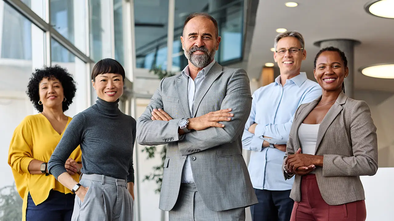 Confident diverse business team smiling and posing with arms crossed in modern office.