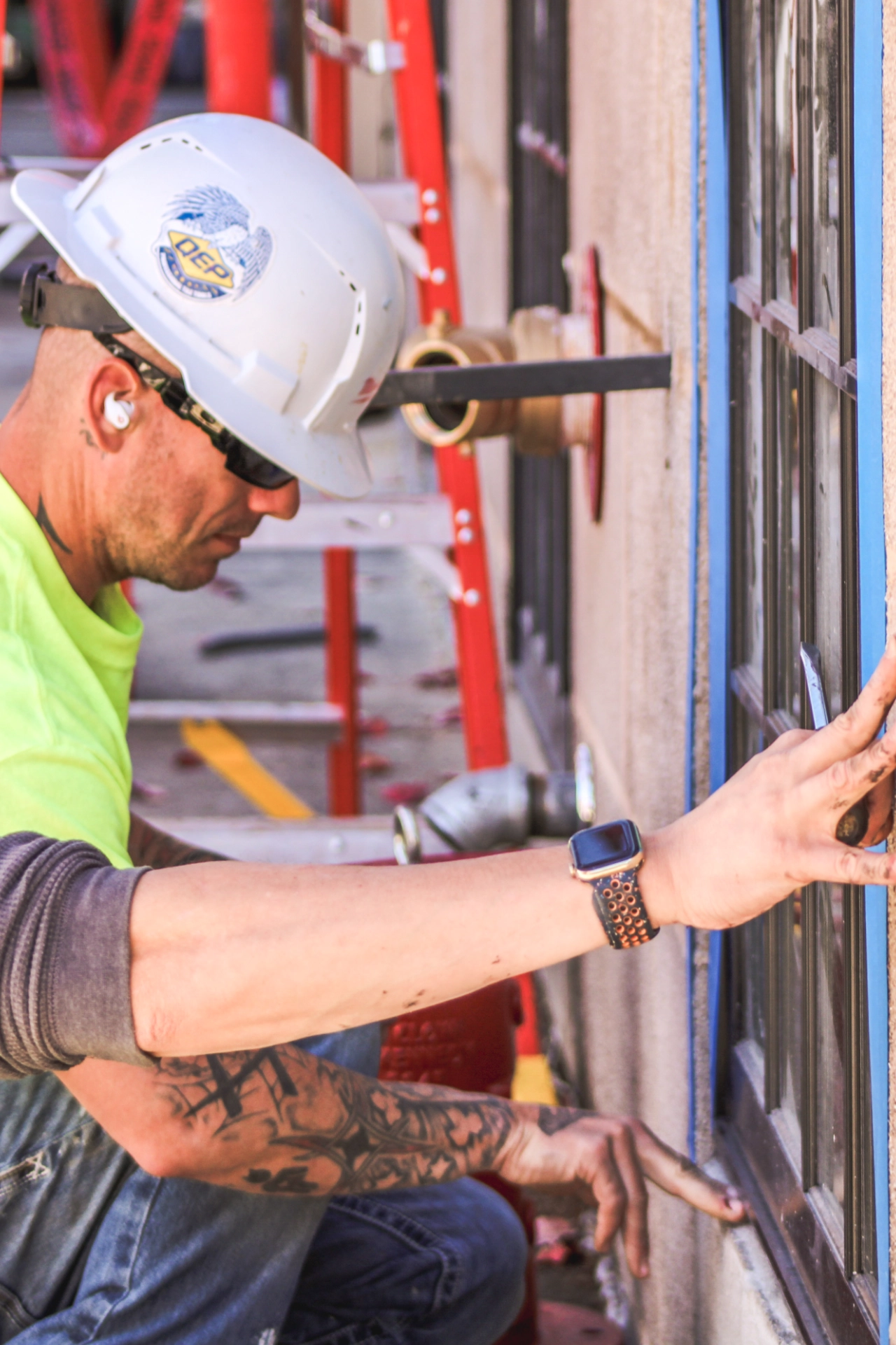 Construction worker installing a windows while using blue tape to mark edges
