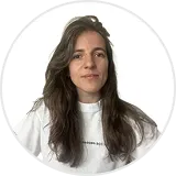 Woman with long dark hair wearing a white top, facing forward with a neutral expression.