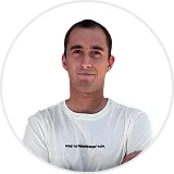 Man with short dark hair wearing a white t-shirt with folded arms against a white background.
