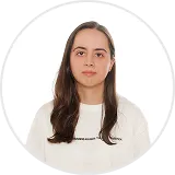Portrait of a woman with long dark hair wearing a white top against a plain white background.
