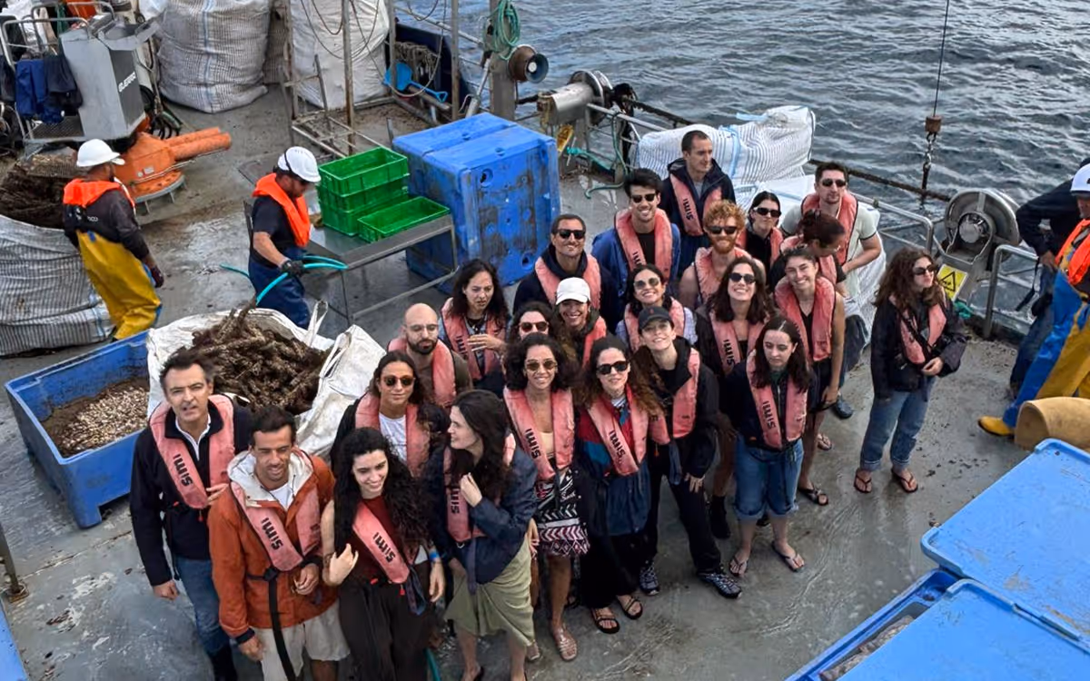 Group of people wearing pink life jackets on a fishing boat near water.