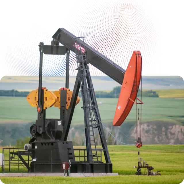 Pumpjack oil pump extractor with a red counterweight operating in a green field with hills in the background.