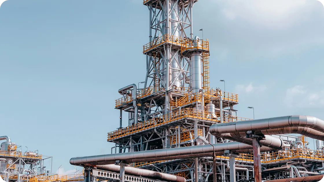 Industrial refinery structure with pipes and metal framework against a clear sky.