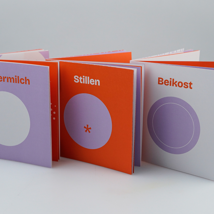 Opened booklet with colorful pages displaying German words and abstract circular shapes.