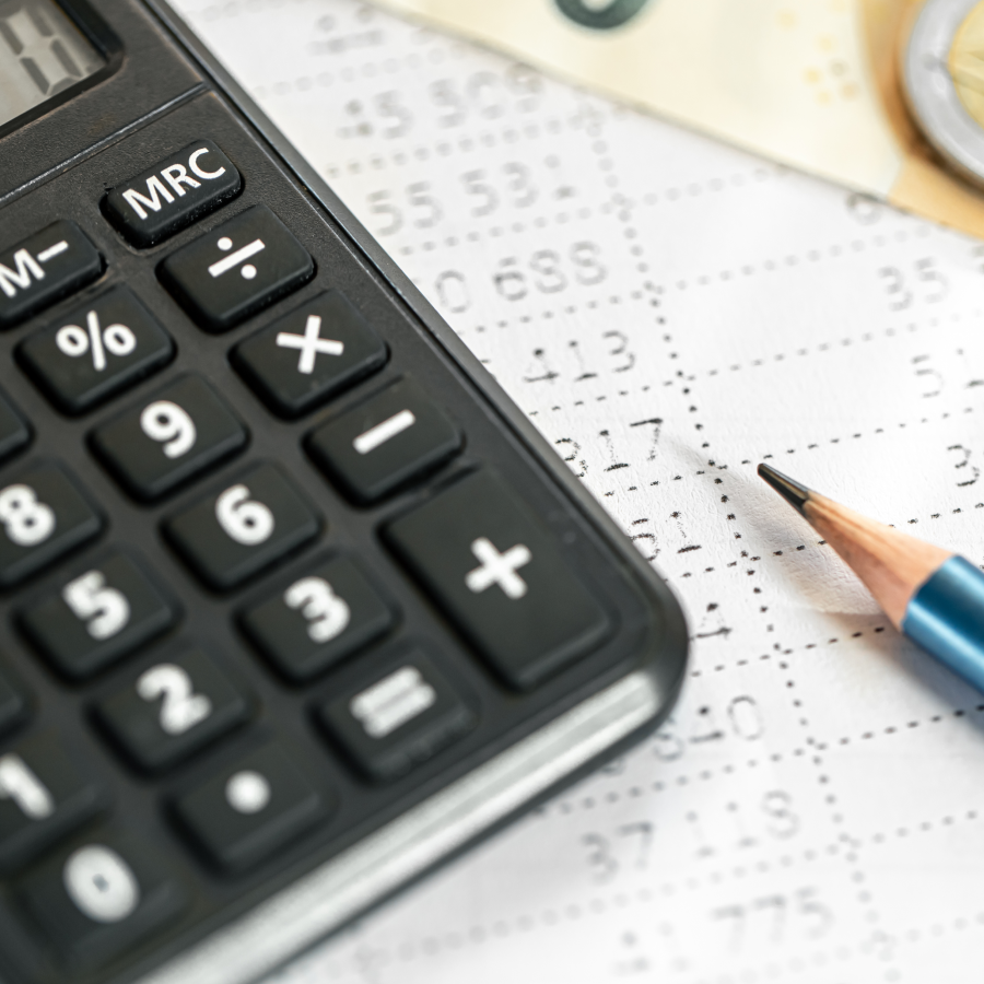 Close-up of a black calculator and a pencil on a financial document with printed numbers and a coin.