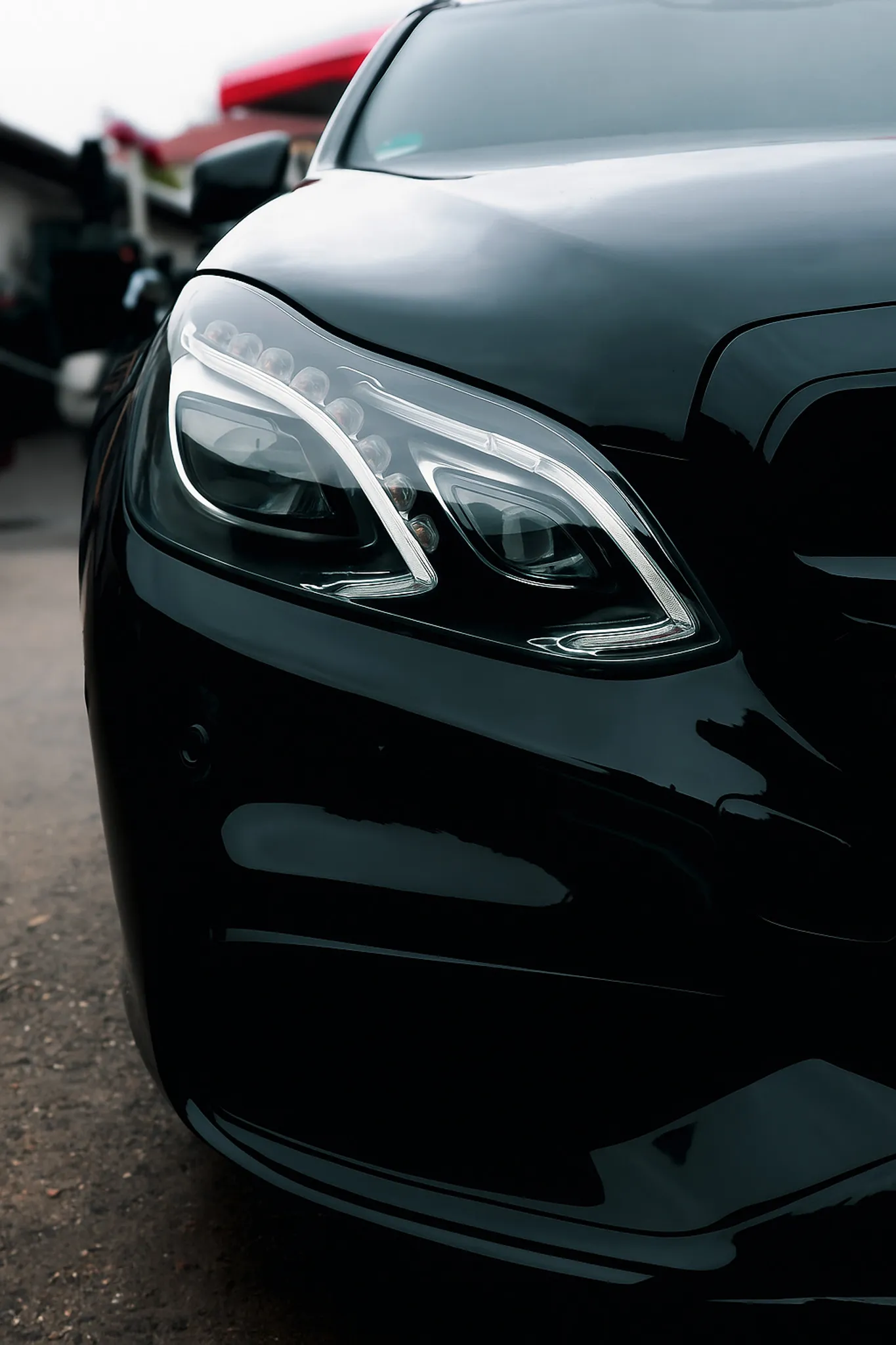 Nahaufnahme der Frontscheinwerfer eines glänzend schwarzen Luxusautos.