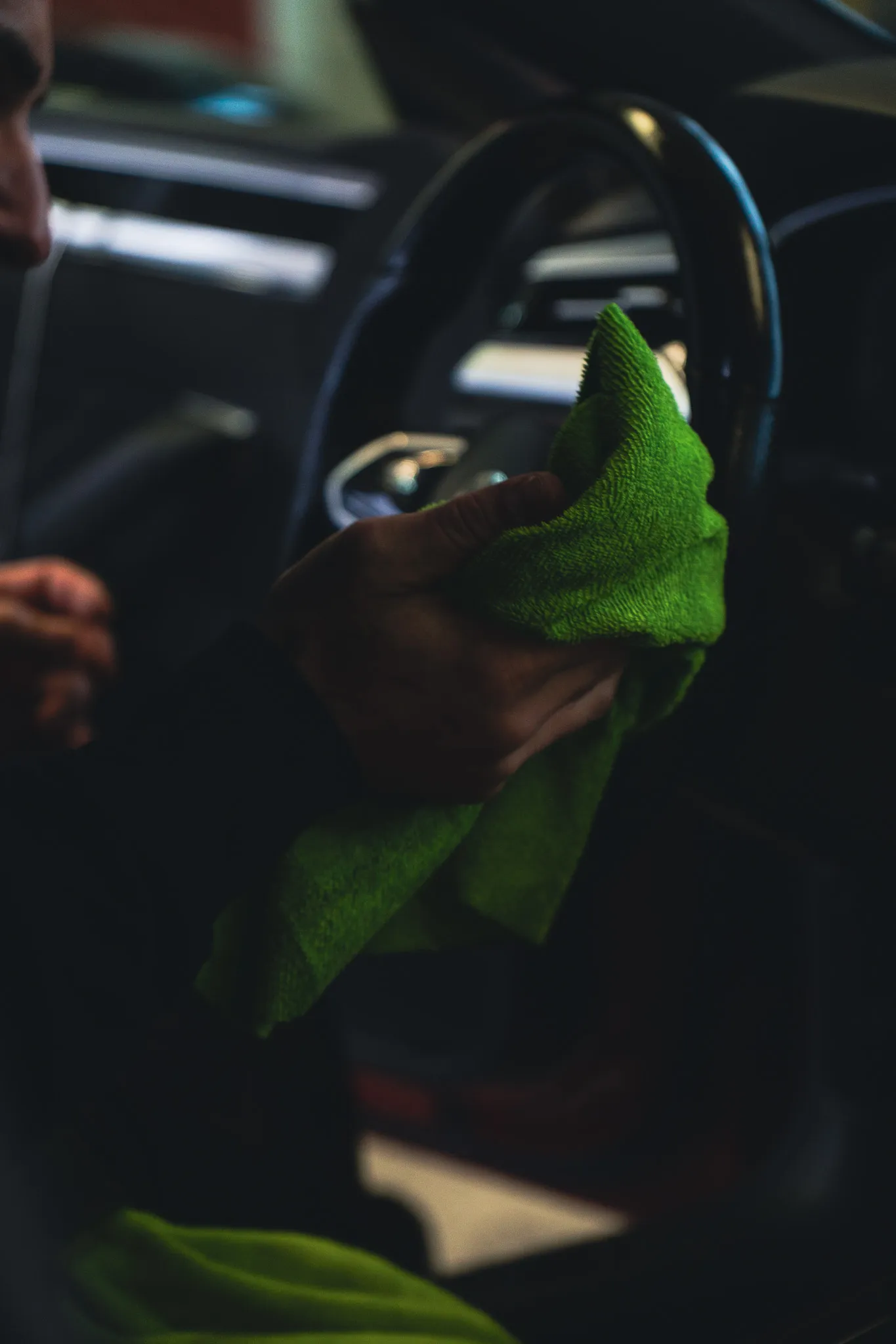 Person wischt mit grünem Tuch ein Autos-Lenkrad ab.