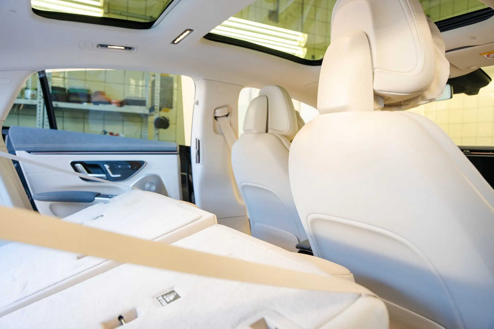 Innenraum eines Fahrzeugs mit umgeklappten Rücksitzen und hellen Ledersitzen.