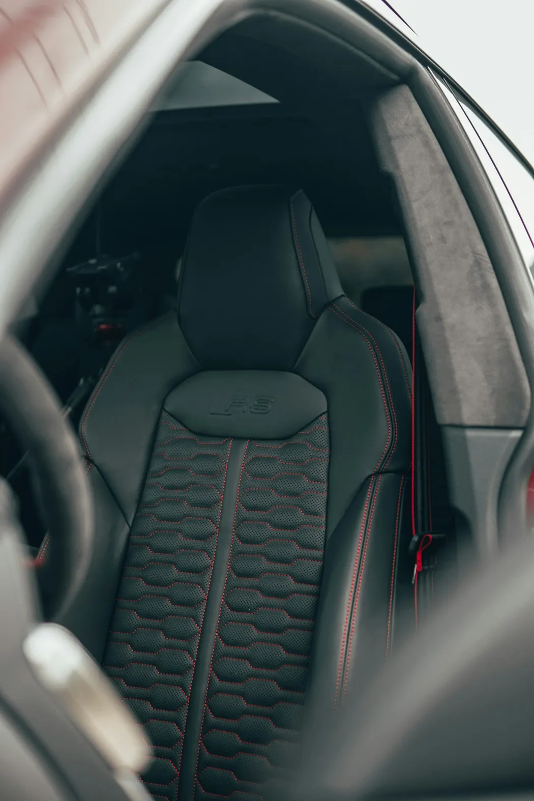 Sportsitz eines Autos mit schwarzem Leder und roten Nähten, geprägt mit dem RS-Logo.