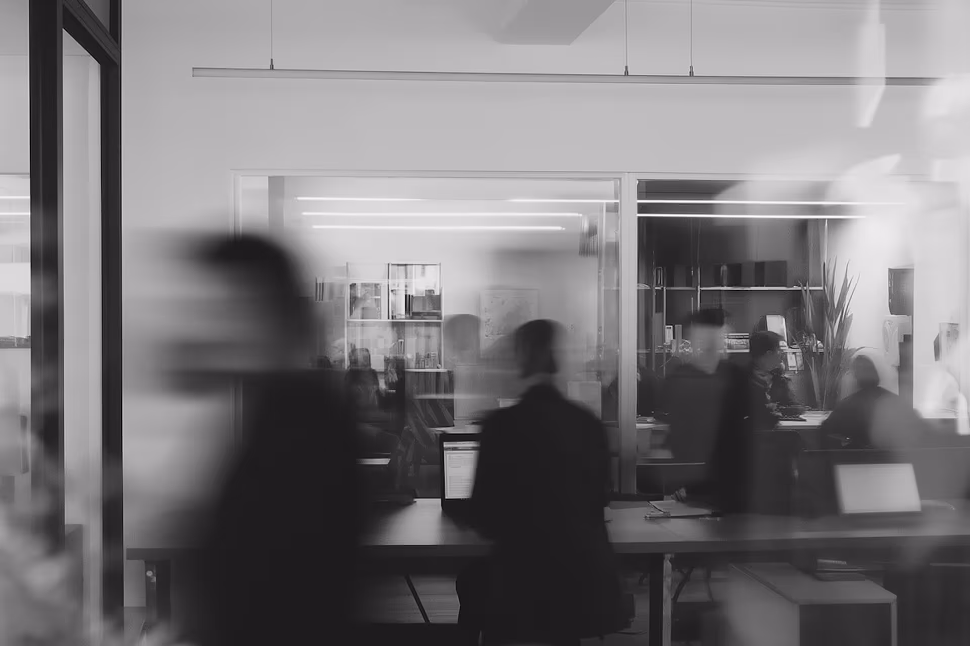 Pessoas em movimento em escritório moderno com pessoas trabalhando em computadores ao fundo.