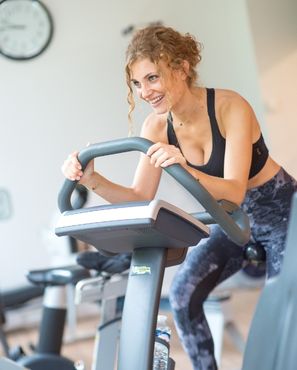 Femme souriante faisant du vélo d'appartement dans une salle de sport.