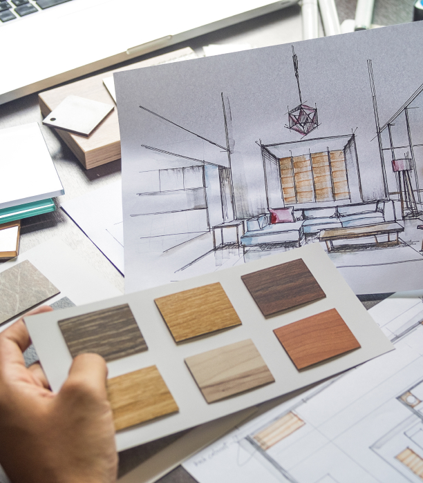 Mano che tiene campioni di legno davanti a un disegno di design d'interni con mobili e lampada moderna.