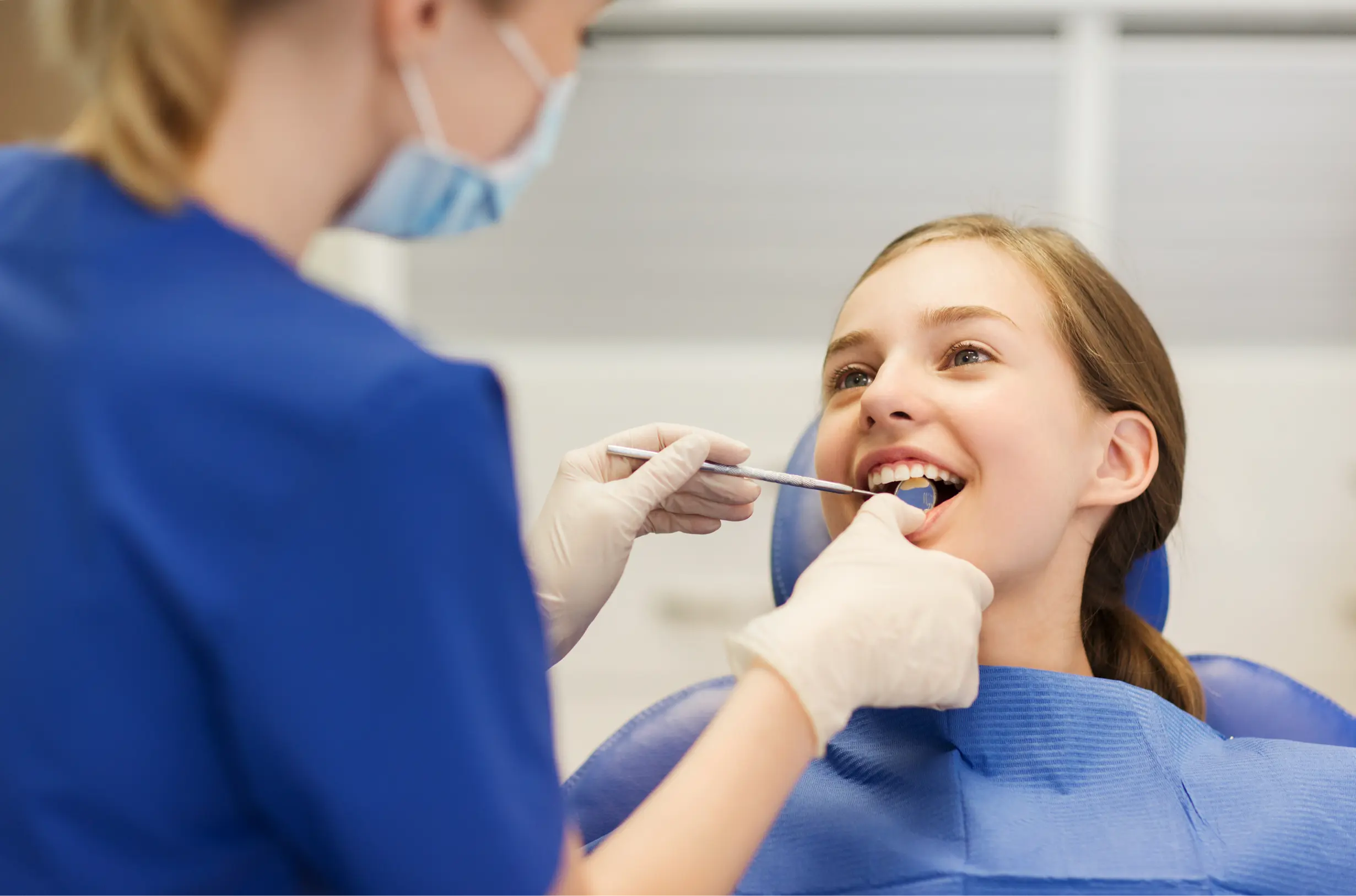 A dental hygienist provides a preventive cleaning, using instruments to remove plaque from a young patient’s teeth during a general dentistry appointment.