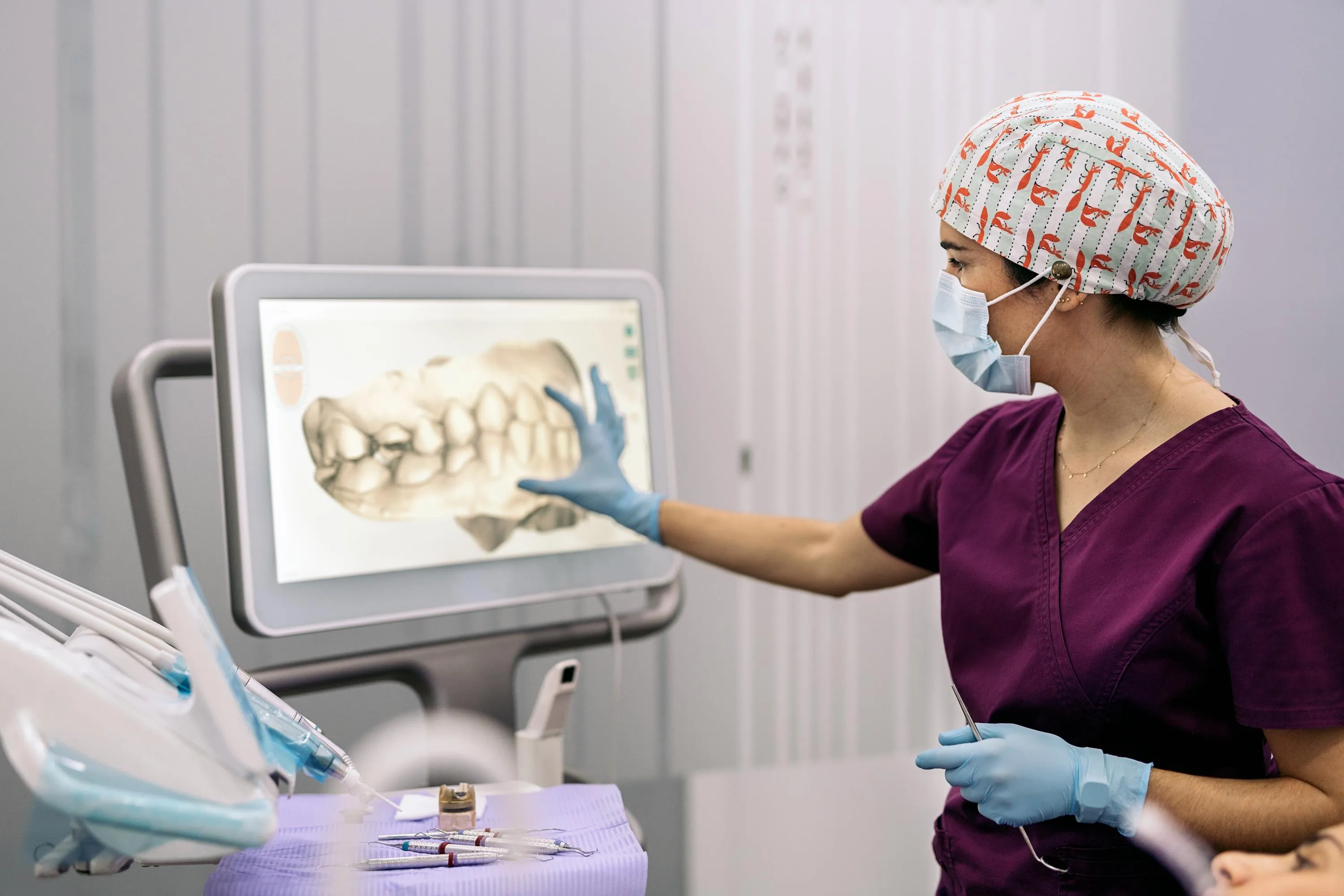 A dental provider points to a detailed 3-D jaw and tooth image displayed on a touchscreen monitor, demonstrating how advanced imaging is used for accurate diagnosis and treatment planning.