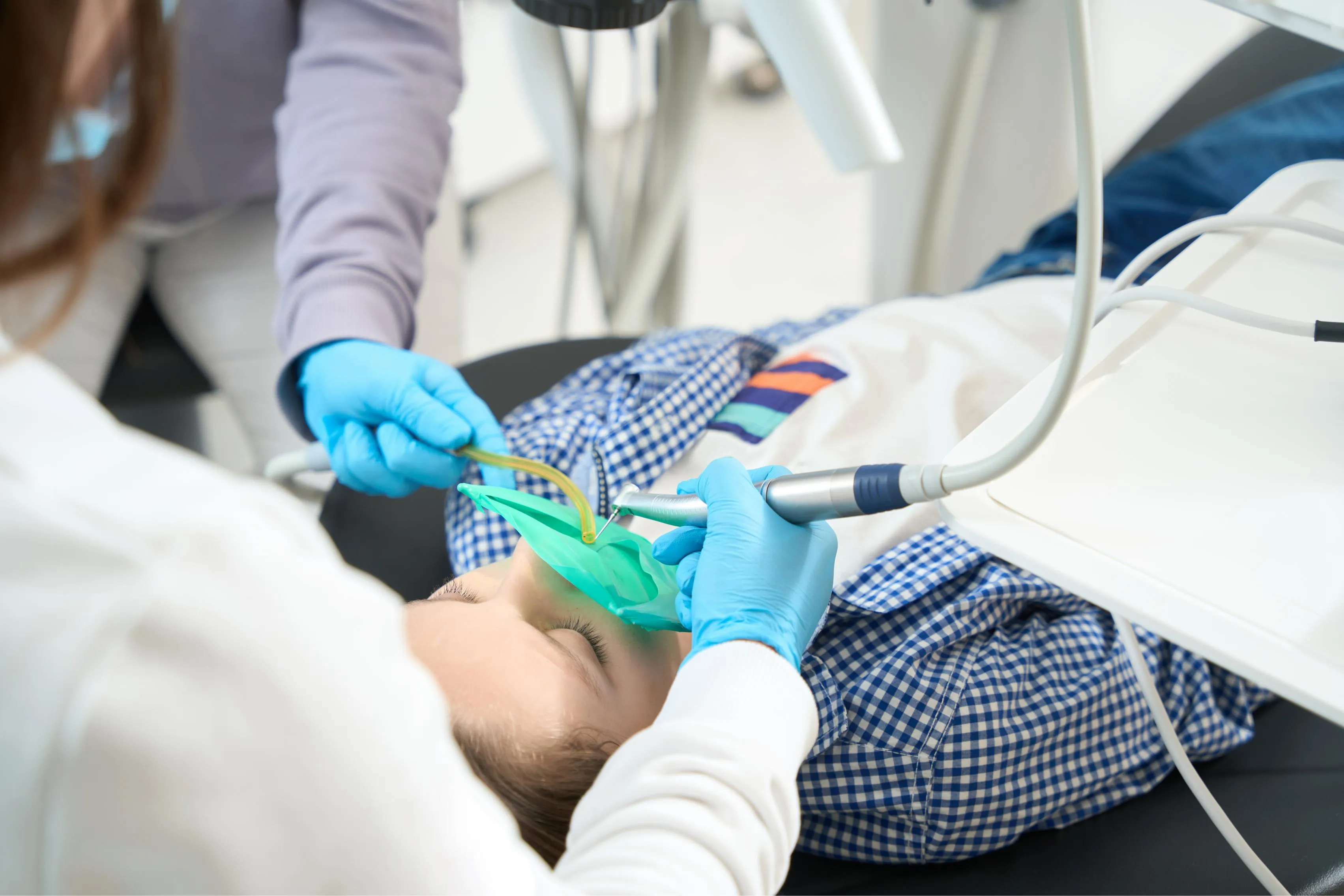 A dental professional administers nitrous oxide sedation to a patient using a nasal mask while monitoring vital signs during a dental treatment.