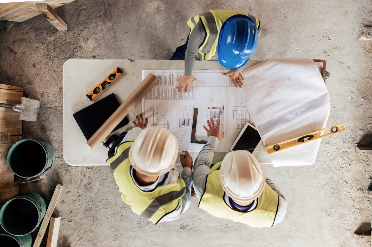 Drei Bauleiter am Planungstisch einer Baustelle