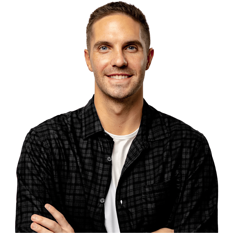 Portrait of a man in a black flannel shirt and white t-shirt, arms crossed, smiling against a light gray background.