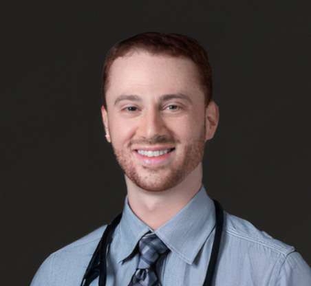 Portrait of a smiling male doctor wearing a dress shirt, tie, and stethoscope against a dark background.