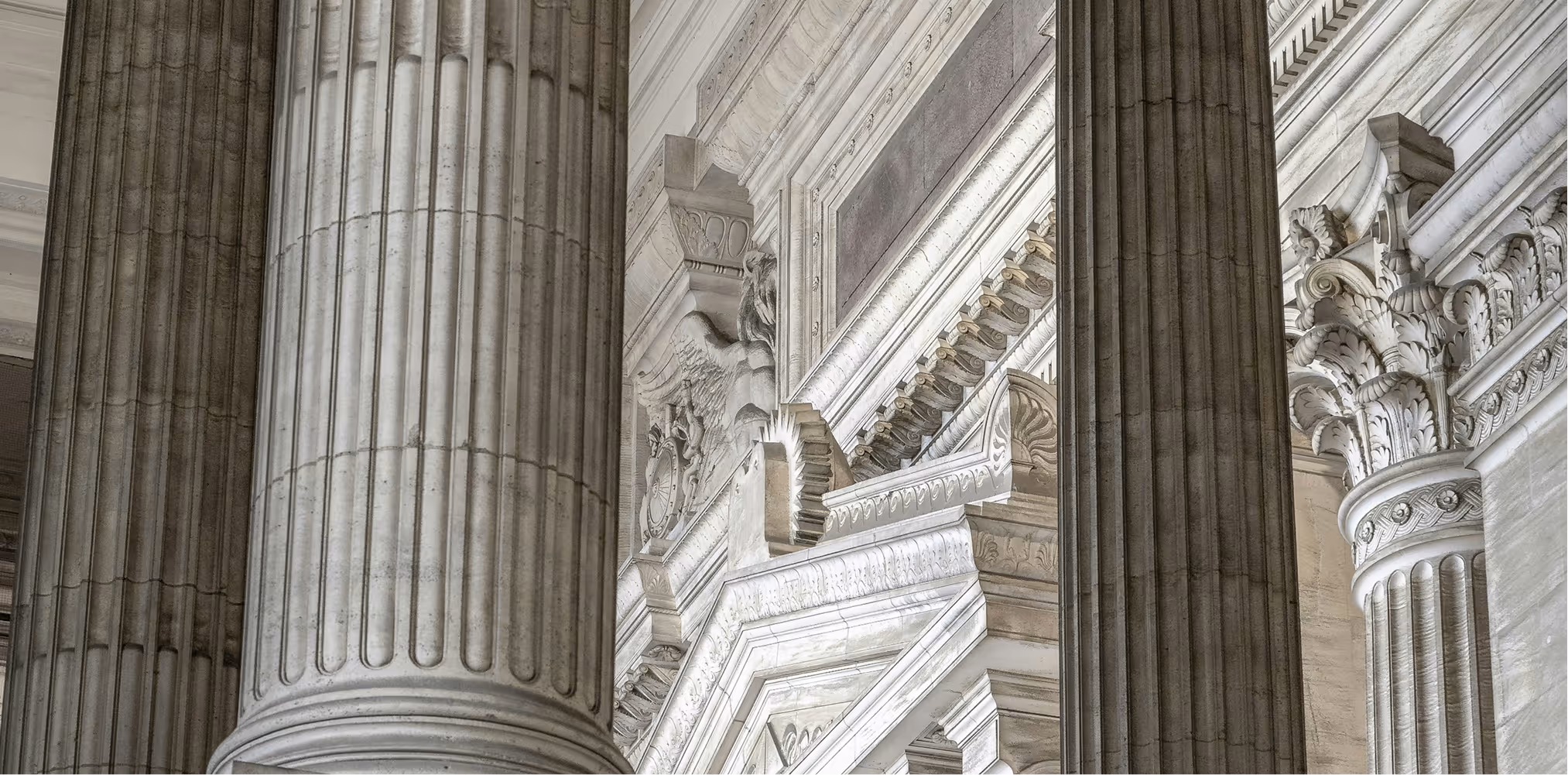 Close-up of ornate classical white stone columns and detailed architectural carvings in a historic building.